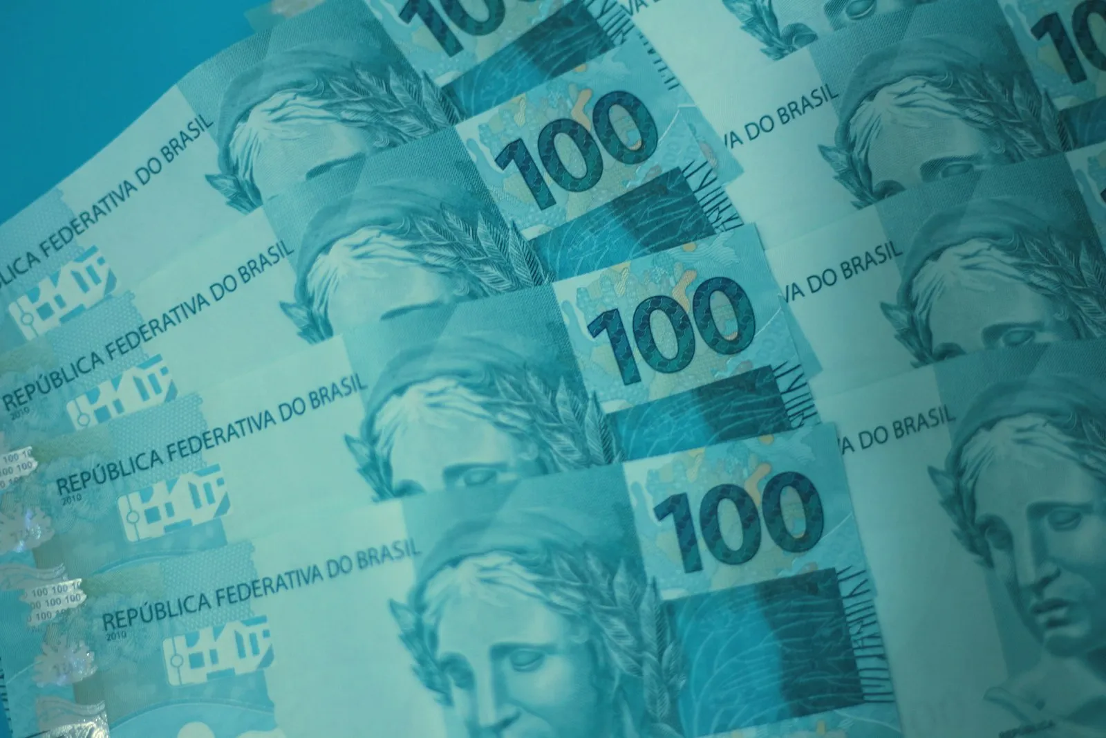 Mãos consultam um aplicativo bancário e anotam dados para pedir portabilidade de salário.